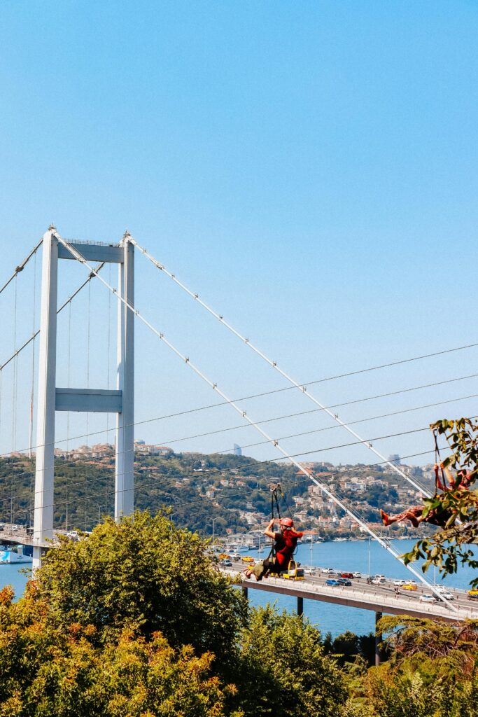 Adventurer zip lining over Istanbul's Bosphorus Strait with skyline view.