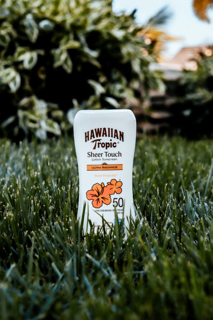 Close-up of Hawaiian Tropic sunscreen with green grass background