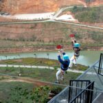 anmol Two people zip lining over a picturesque valley, capturing the thrill of adventure sports.