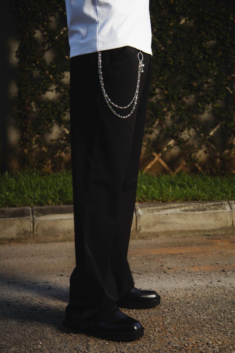Chic trousers with a stylish chain accessory against a natural outdoor backdrop.
