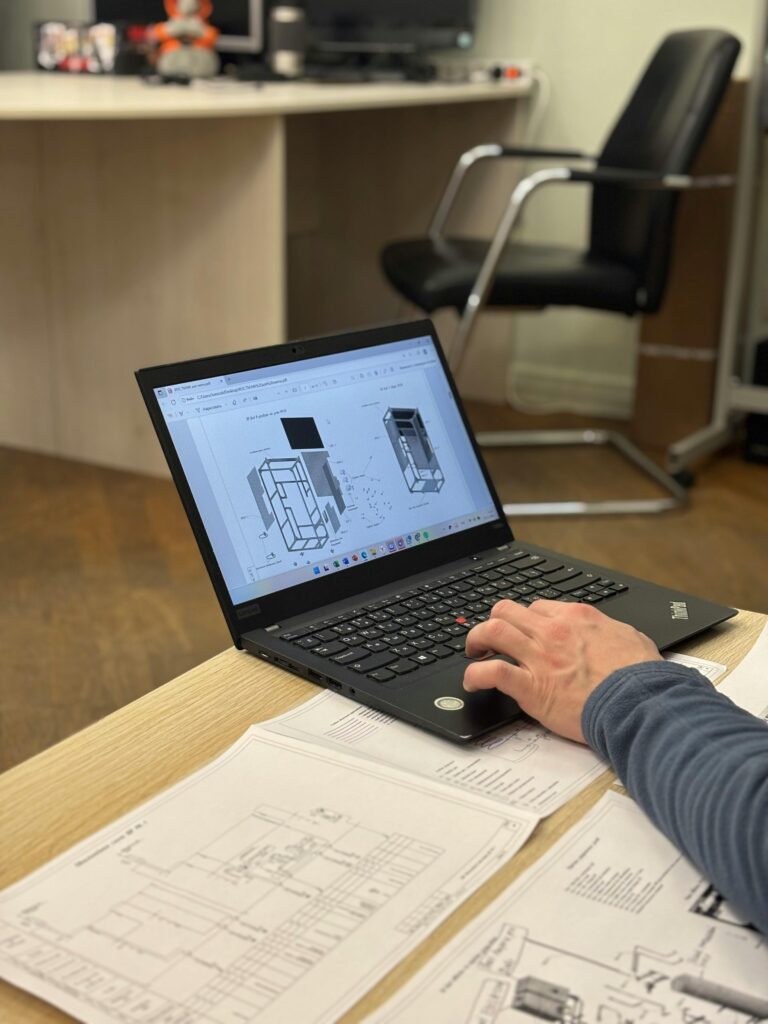 Investing An engineer reviews detailed blueprints on a laptop at an office desk.