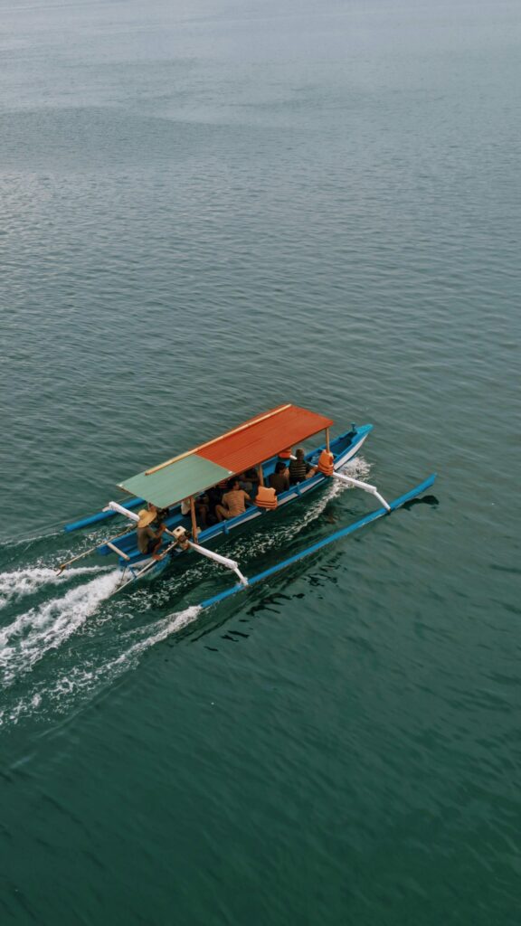 A colorful traditional boat cruises on the serene waters of Nusa Tenggara Barat, Indonesia.